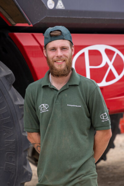 A photo of Kieran Robinson of P.X. Farms in front of a red P.X Farms vehicle