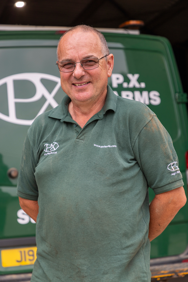 Simon Worboys standing posing for the camera with his hands behind his back and a green PX Farms vehicle in the background